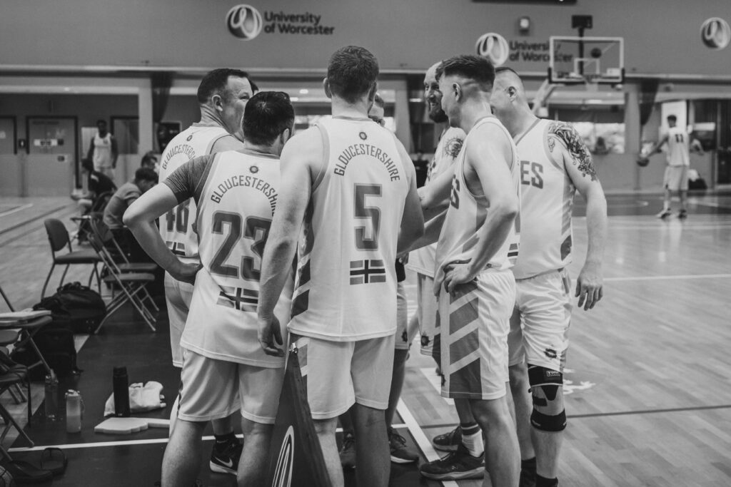 Black and white photo. A group of basketball players huddle during. timeout